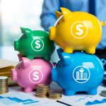 A stack of colorful piggy banks with various symbols representing different tax-advantaged savings accounts, surrounded by financial documents and charts